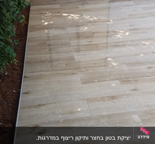 ריצוף חדש מעץ בחצר עם קיר חיצוני